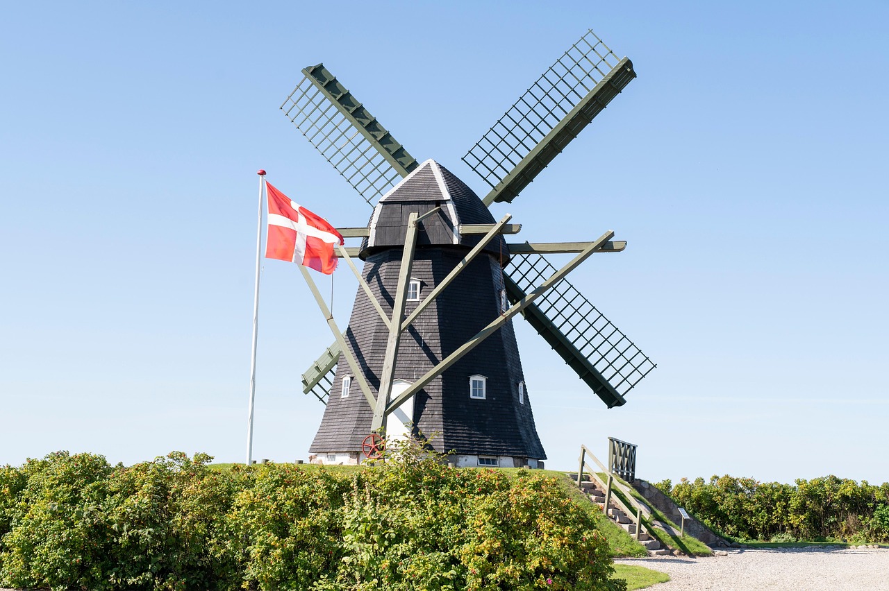 Eine alte Windmühle und dänischer Flagge vor blauem Himmel